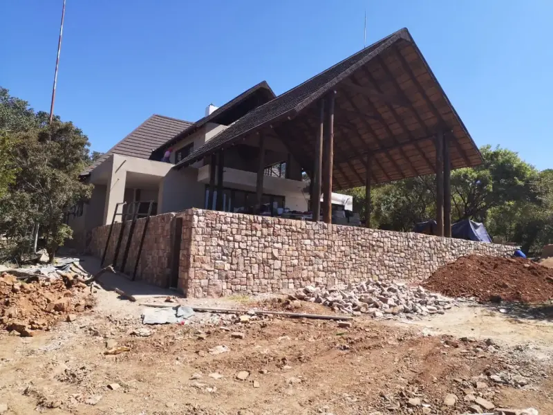 House under construction with stone wall and timber gable, Mabula